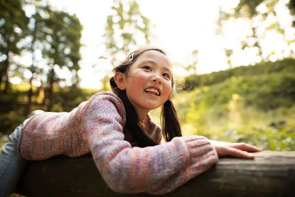 Young happy girl laid on a tree