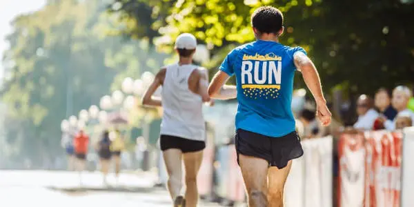 The backs of two male runners, running in a marathon