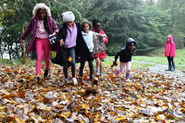 Group of girls running through autumn leaves
